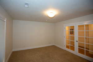 Carpeted bedroom with french doors and a textured ceiling