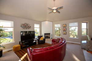 Living room featuring a tiled fireplace, carpet, and ceiling fan