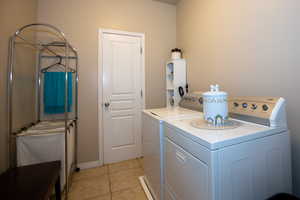 Clothes washing area with washing machine and dryer and light tile patterned floors