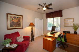 Carpeted home office/bedroom featuring ceiling fan