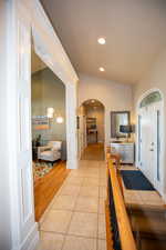 Hallway with light tile patterned floors and vaulted ceiling