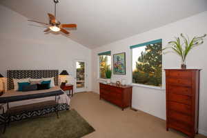 Master bedroom with ceiling fan, access to exterior, and vaulted ceiling