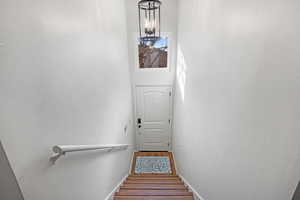 Stairway featuring hardwood / wood-style flooring, a chandelier, and a high ceiling