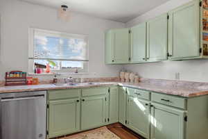 Kitchen featuring green cabinets, dishwasher, sink, and hardwood / wood-style floors