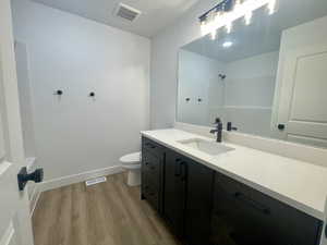 Bathroom with hardwood / wood-style flooring, vanity, toilet, and a shower