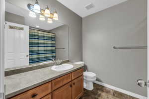 Bathroom with vanity, toilet, and curtained shower