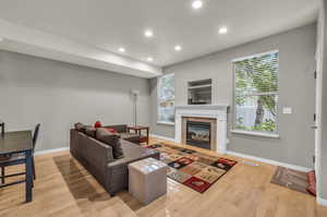 Living room with a tiled fireplace and light hardwood / wood-style flooring