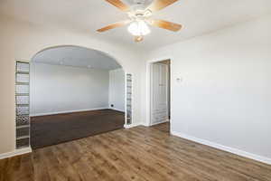 Unfurnished room featuring built in features, hardwood / wood-style floors, and ceiling fan