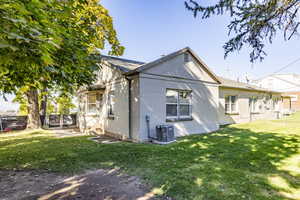 Rear view of property featuring cooling unit and a yard