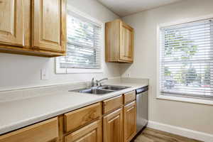 Kitchen with stainless steel dishwasher, sink, and light hardwood / wood-style floors