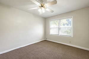 Carpeted empty room featuring ceiling fan