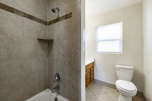 Full bathroom with toilet, tiled shower / bath combo, vanity, and tile patterned flooring