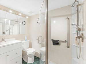 Bathroom with toilet, an enclosed shower, a textured ceiling, and vanity