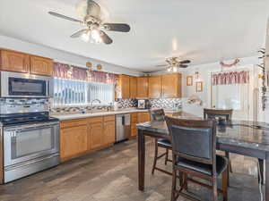 Kitchen featuring appliances with stainless steel finishes, decorative backsplash, sink, and ceiling fan