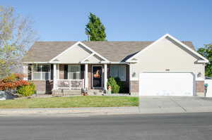 View of front of property with a porch, a front lawn, and a garage