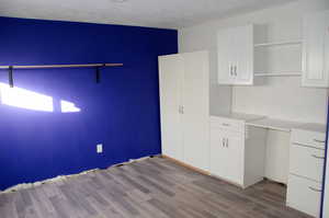 Craft room featuring white cabinets, a textured ceiling, and light hardwood / wood-style floors