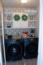 Washroom featuring a textured ceiling, washer and dryer, hardwood / wood-style flooring, and cabinets