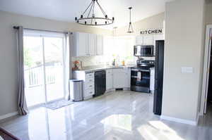 Kitchen featuring white cabinetry, black appliances, vaulted ceiling, and pendant lighting