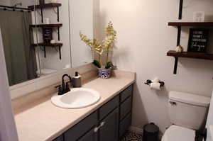 Bathroom with vanity, a shower with curtain, and toilet