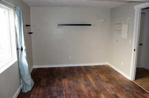 Spare room featuring a textured ceiling and dark hardwood / wood-style floors