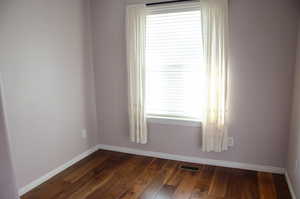 Empty room featuring dark wood-type flooring