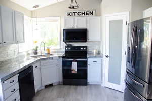 Kitchen featuring white cabinetry, black appliances, decorative light fixtures, and sink