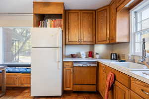 Kitchen featuring white fridge, dishwashing machine, a wealth of natural light, and sink