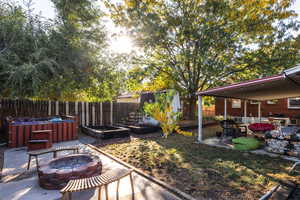 View of yard with a patio area, a hot tub, a fire pit, and a storage shed