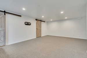 Carpeted spare room with a barn door