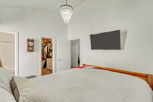 Bedroom with a spacious closet, an inviting chandelier, and high vaulted ceiling