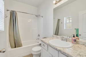 Full bathroom with toilet, shower / tub combo with curtain, and vanity