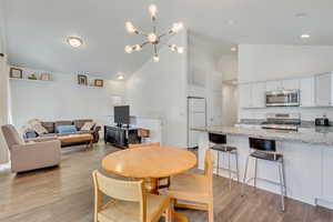 Dining room with an inviting chandelier, high vaulted ceiling, and light wood-type flooring