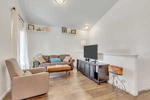 Living room with vaulted ceiling and light wood-type flooring