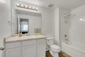 Full bathroom featuring vanity, toilet, a textured ceiling, and tub / shower combination