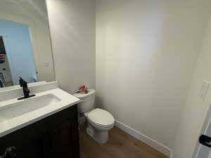 Bathroom with hardwood / wood-style floors, vanity, and toilet