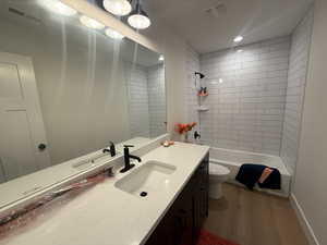 Full bathroom featuring vanity, hardwood / wood-style floors, tiled shower / bath combo, and toilet