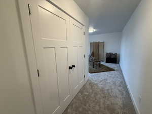 Hallway featuring carpet flooring and a textured ceiling