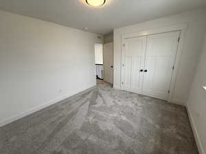 Unfurnished bedroom featuring light carpet, a closet, and a textured ceiling