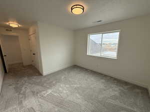 Empty room with carpet flooring and a textured ceiling