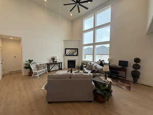 Living room featuring a high ceiling, light hardwood / wood-style floors, and ceiling fan