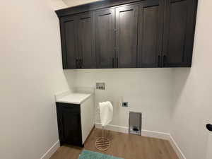 Clothes washing area featuring electric dryer hookup, light hardwood / wood-style floors, cabinets, and washer hookup