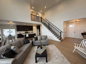 Living room with a healthy amount of sunlight, an inviting chandelier, a high ceiling, and light hardwood / wood-style flooring