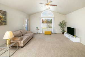 Living room featuring lofted ceiling, light carpet, and ceiling fan