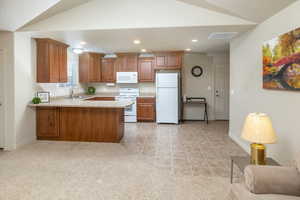 Kitchen featuring sink, kitchen peninsula, light colored carpet, and white appliances