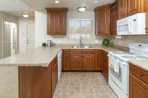 Kitchen with white appliances, sink, and kitchen peninsula