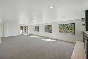 Unfurnished living room featuring light carpet, a textured ceiling, and a fireplace