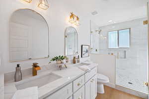 Bathroom with toilet, walk in shower, vanity, and wood-type flooring