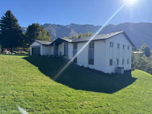 View of front of property with central air condition unit, a mountain view, a front lawn, and a garage