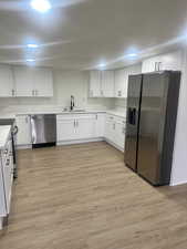 Kitchen with white cabinetry, sink, light hardwood / wood-style floors, and stainless steel appliances