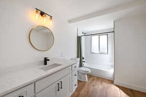 Full bathroom featuring shower / tub combo with curtain, vanity, hardwood / wood-style flooring, and toilet